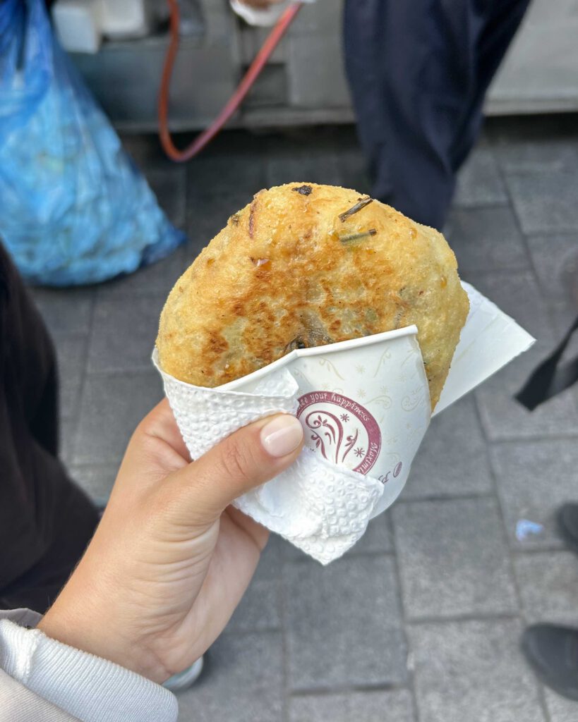 Solo female traveller holding a japchae hotteok from Namdaemun Market Seoul