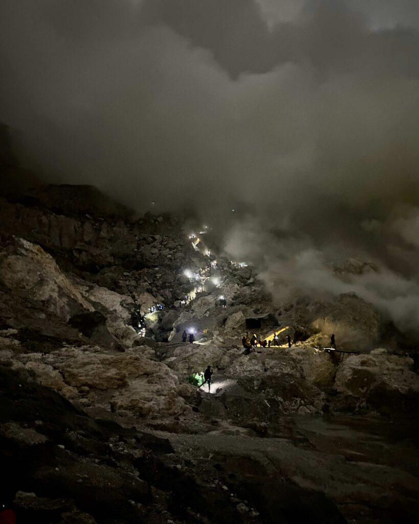 Hikers climbing down into the Mount Ijen crater with sulphur smoke clouds East Java Indonesia