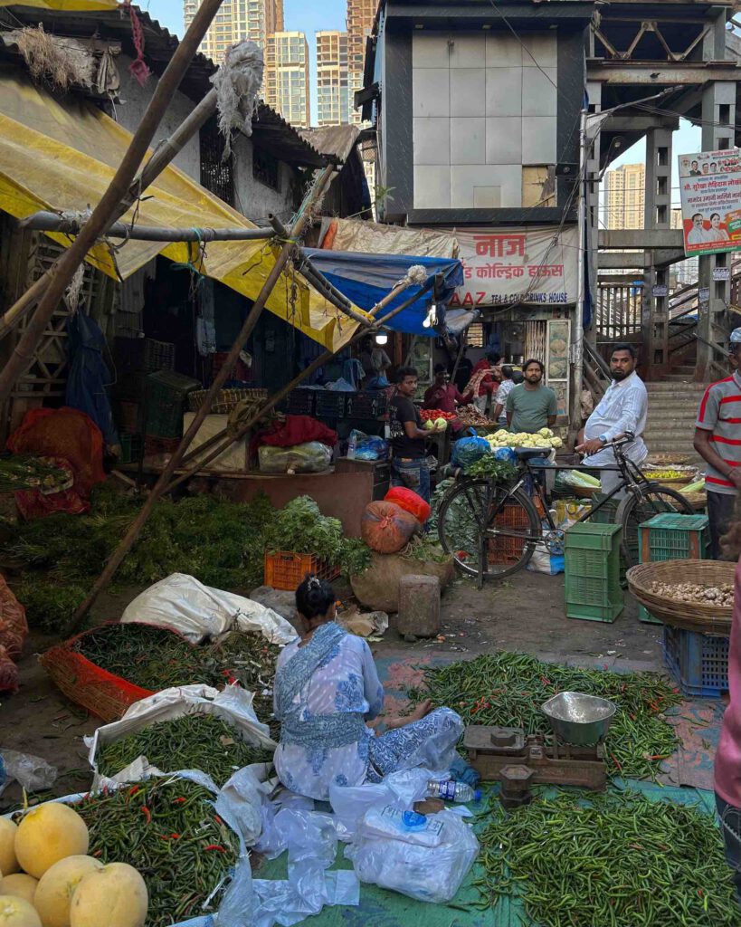 A food market in the early morning in Mumbai with a women sorting food and males on bikes
