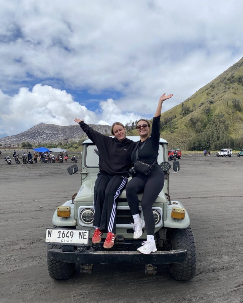 Solo female travellers sitting on top of a jeep on the volcanic plains of Mount Bromo East Java Indonesia with Mador Hostel