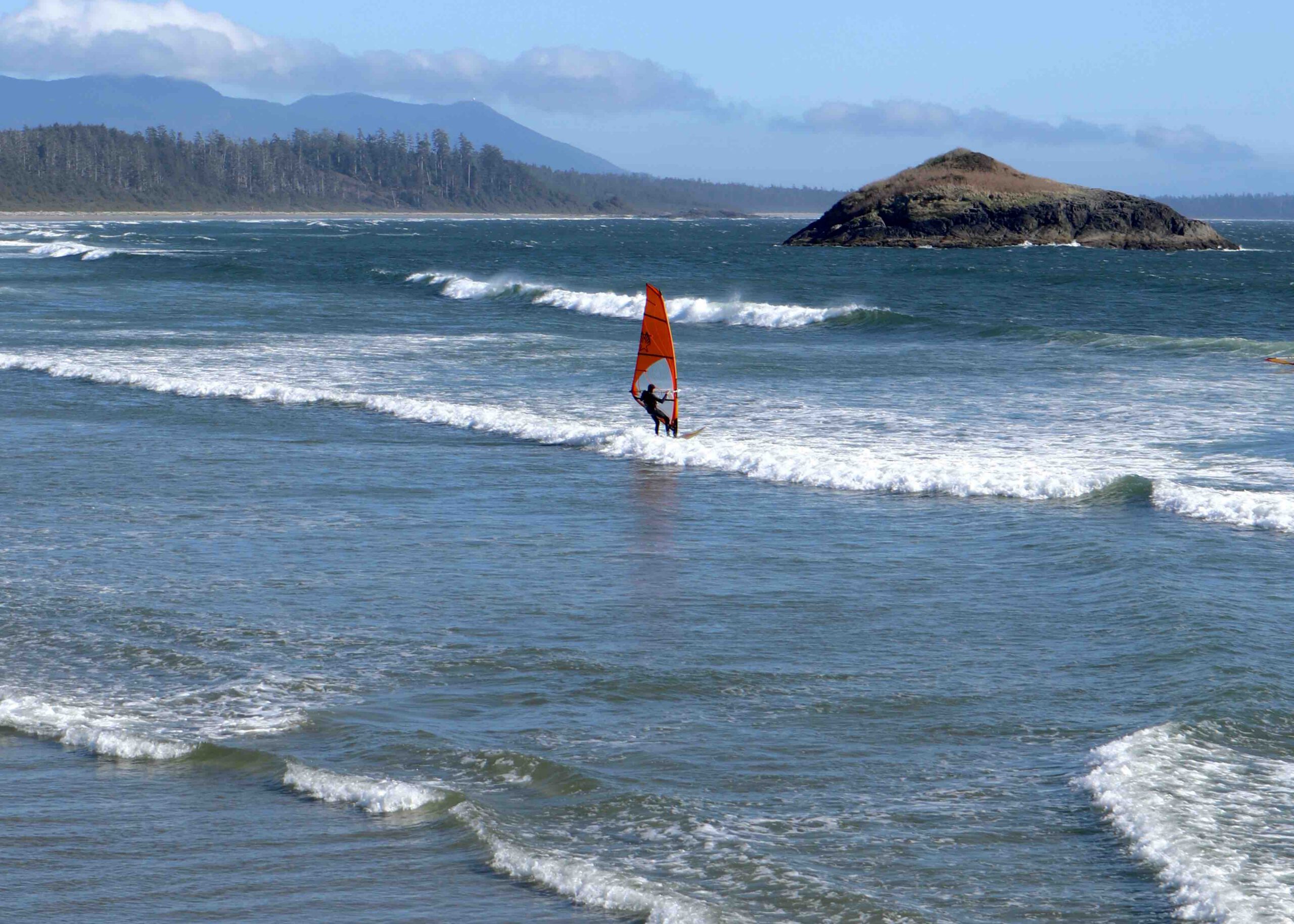Wind surfer riding waves at Long beach in Tofino British Columbia in spring