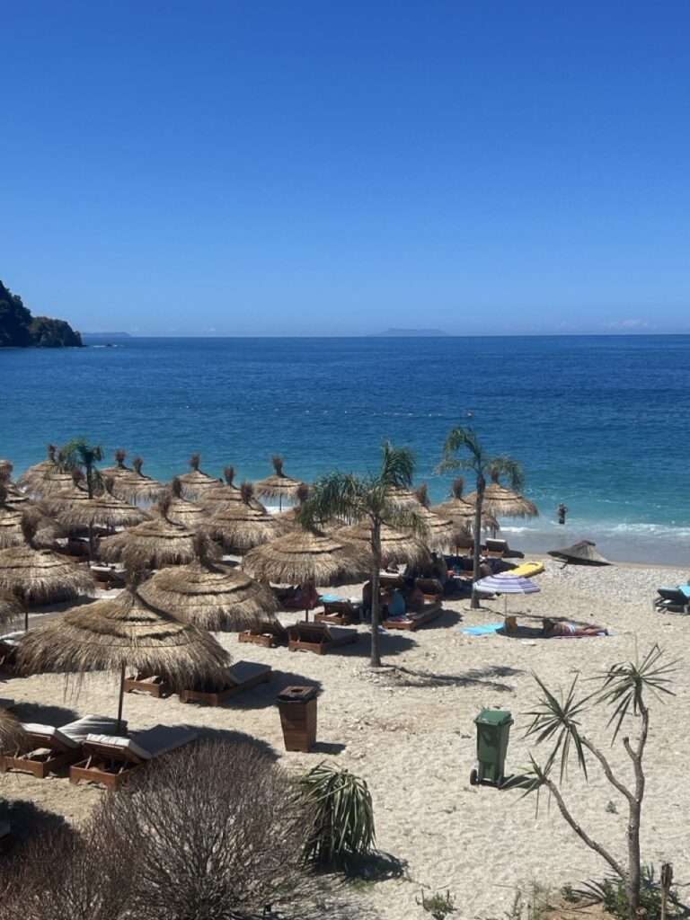 Beach umbrellas and turquoise water in Himarë, Albania